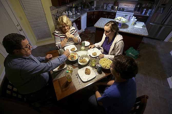 In this photo made Monday, Oct. 21, 2013, Bakir Avdagic, left, sits down to dinner with his wife, Mirha, top, daughter Selma, 22, and son, Amer, 18, bottom right, at their home in O'Fallon, Mo. The Avdagic family are part of an estimated 60,000 Bosnians who live in the St. Louis metropolitan area, making it the largest such settlement outside the country now known as Bosnia-Herzegovina.