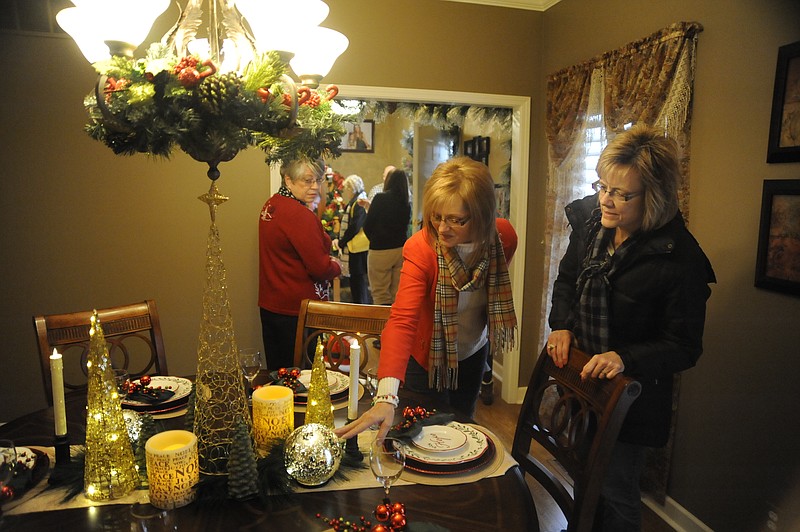 Mary Jo Henke reaches to touch the blown glass mercury spheres at the center of Marlene Carlson's dining room table during Sunday's annual Heisinger Auxiliary Christmas Homes Tour. Touring with her at right is Dianne Williams.