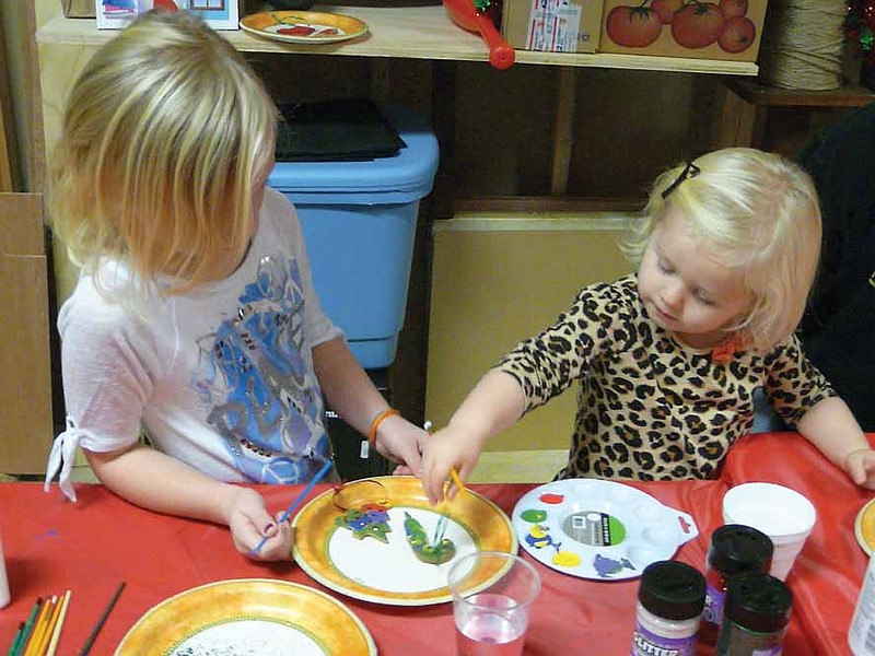 Claire Peterson, 6, and Charlee Peterson, 2, daughters of Lesha and Marc Peterson, California, make Christmas ornaments in Santa's Workshop at the Winding Road gift store open house, Saturday, Dec. 7.