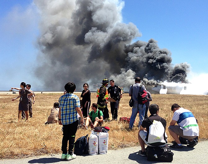 Passenger Benjamin Levy took this photo of fellow passengers from Asiana Airlines flight 214, many with their luggage, on the tarmac just moments after the plane crashed July 6 at the San Francisco International Airport in San Francisco. According to an investigative report released Wednesday, the Asiana Airlines captain who crashed the airplane in July told investigators he was "very concerned" about attempting a visual approach because the runway's automatic landing aids were out of service due to construction. The jet crash landed after approaching low and slow in an accident that left three dead and more than 200 injured, according to the National Transportation Safety Board. The investigative report was released at the start of a daylong NTSB hearing into the accident.