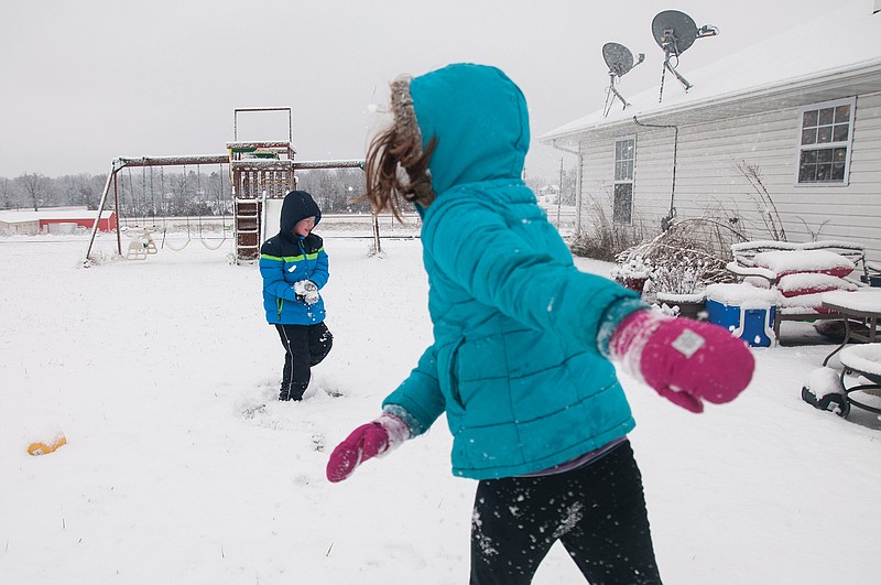 (From left to right) Noah Cerneka, 7, tightly closes his eyes and forms a snow ball as his sister Madeleine Cerneka, 9, throws at snow at him in their backyard on Saturday.