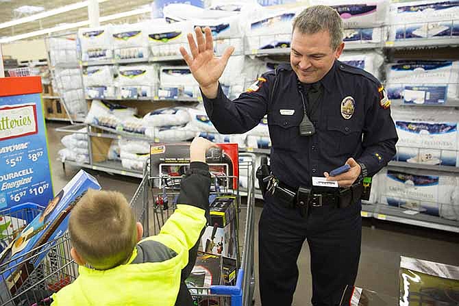 Officer Les Martin, from the Jefferson City Police Department, high fives Matthew Baim, 5, after picking up a copy of Battleship during Operation TOYS (Take Our Youth Shopping) Saturday morning.