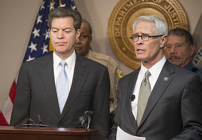 Kansas Gov. Sam Brownback, left, listens as U.S. Attorney Barry Grissom announces the arrest of Terry Lee Loewen, 58, of Wichita, Kan., during a news conference on Friday, Dec. 13, 2013, in Witchita, Kan. Grissom said Loewen was arrested Friday morning at Mid-Continent regional airport where he planned to drive a car that he believed was full of explosives into a terminal at the airport. (AP Photo/The Wichita Eagle, Travis Heying)