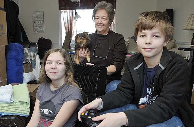 Aleksandra, 12, and her brother Nicolai Ivanov, 11, pause from playing a video game to pose for a photograph with their mother, Gaila Trusty, and the family's chihuahua, Cocoa, in their Jefferson City home. The siblings were
taken by their Russian father to his home country in July. He had not planned on returning the children to the United States, but Trusty went to Russia and in mid-November was able to bring them home to Jefferson City.