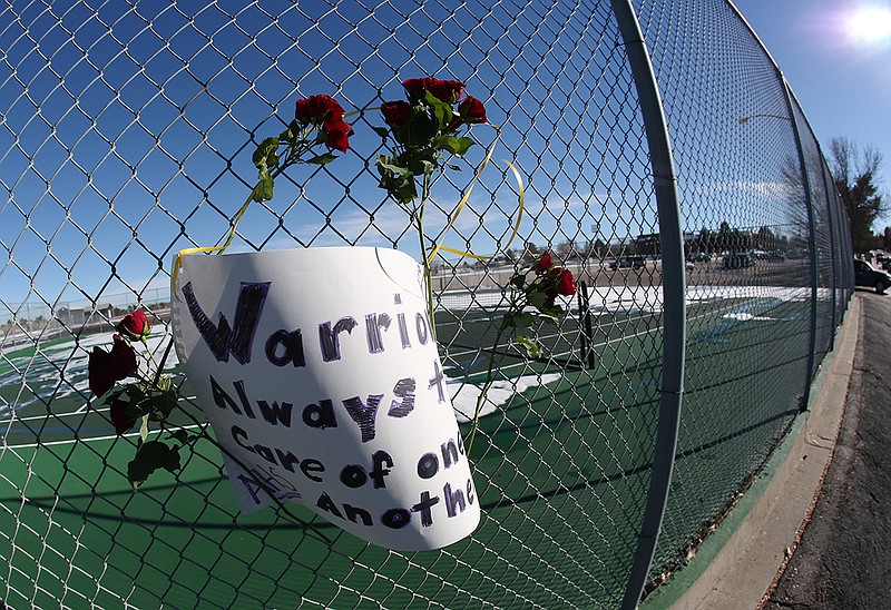 Roses and a sign of support are woven into a cyclone fence around a tennis court at Arapahoe High School in Centennial, Colo.  The school was the scene of a shooting on Friday that left a student gunman dead and two other students injured. 