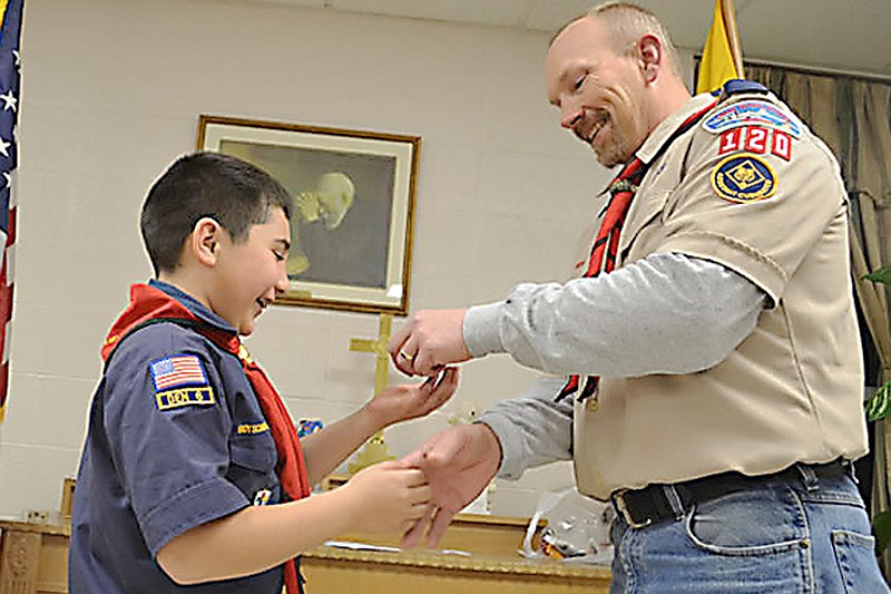 Assistant Cubmaster Brad Friedmeyer presents achievement awards to Diego Vasquez as Cubmaster Cameron Freiner looks on.