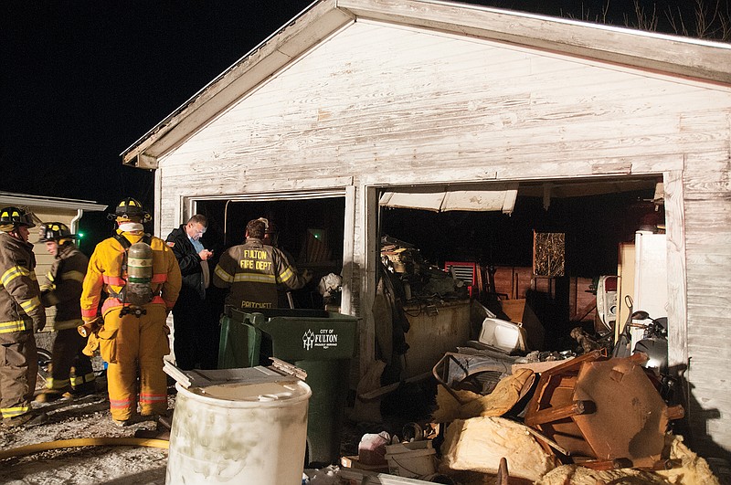 Fulton firefighters assess the damage done to a garage Tuesday on Monroe Street after a fire. The resident was smoking in the garage. His cigarette caught on fire after he set it on the floor where there was gasoline, said Fulton Fire Department Assistant Fire Chief Kevin Coffelt.
