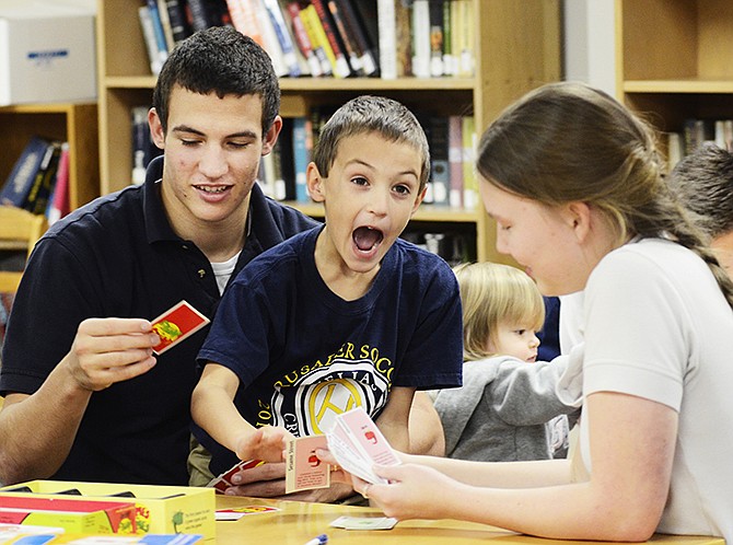 Students in Chris Cooper's psychology class at Helias High School play with and observe young children as part of their class work. Caleb Davidovich gave his older brother, Kyle, and his classmate, Laura Hartman, plenty to report on as they played a card game. 