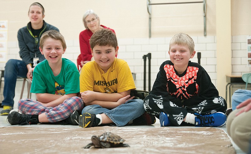 Will Pendleton, Jack Winterbower and C.J. Mullins smile and laugh as a Ouachita Map Turtle walks across the floor on Thursday during Bush Elementary's after-school or BAC PAC program.