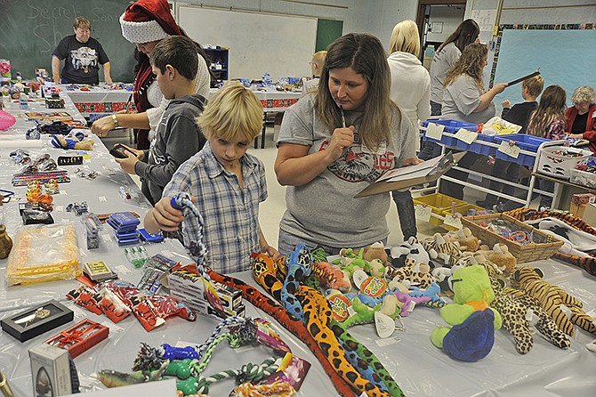 Eugene Elementary School third-grader Jay Bungart picks out a chew toy for his pets with the help of volunteer Melissa Johnson at the Eugene School PTO's recent Secret Santa workshop, where hundreds of students had the opportunity to shop for small gifts to give this Christmas season.