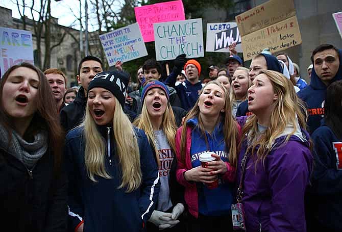 Students sing vocalist Mary Lambert's lyrics to the song "Same Love" by Macklemore & Ryan Lewis outside of the Chancery building for the Archdiocese of Seattle, Friday, Dec. 20, 2013, in Seattle. The students were rallying for Eastside Catholic's Vice Principal Mike Zmuda, who resigned his position after officials with the archdiocese discovered that he was in a same-sex marriage. He was told the marriage violated his contract. (AP Photo/seattlepi.com, Joshua Trujillo)