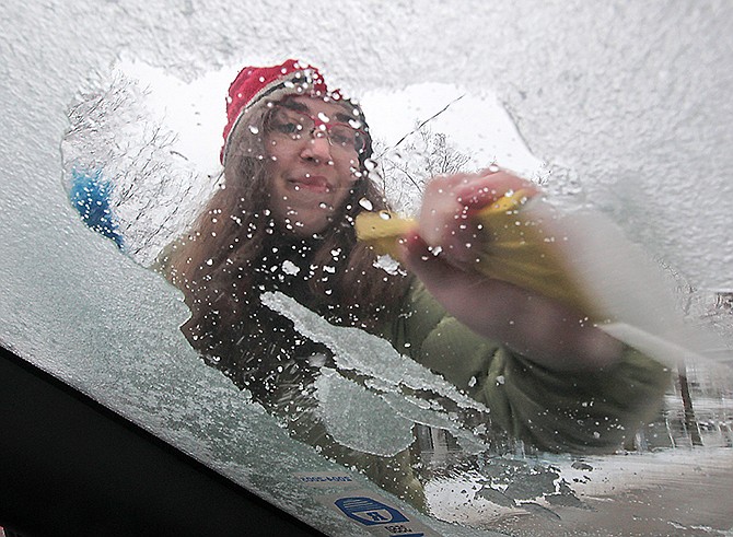 Julia Rhodes works to remove an accumulation of ice from the windshield of her car in Madison, Wis. after freezing rains moved through the area Friday.
