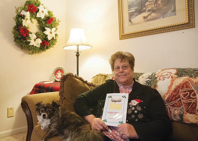 Bonnie Cruickshank, local author, sits in her Fulton home and poses with a copy of her latest children's book, "A Soddy Christmas: A Story of the Prairie." The story is about a family who wonders and worries if the father will be home for Christmas after he is caught in a blizzard. Cruickshank is a member of the writer's workshop at the store Well Read Books and will hold a reading there on Dec. 24.