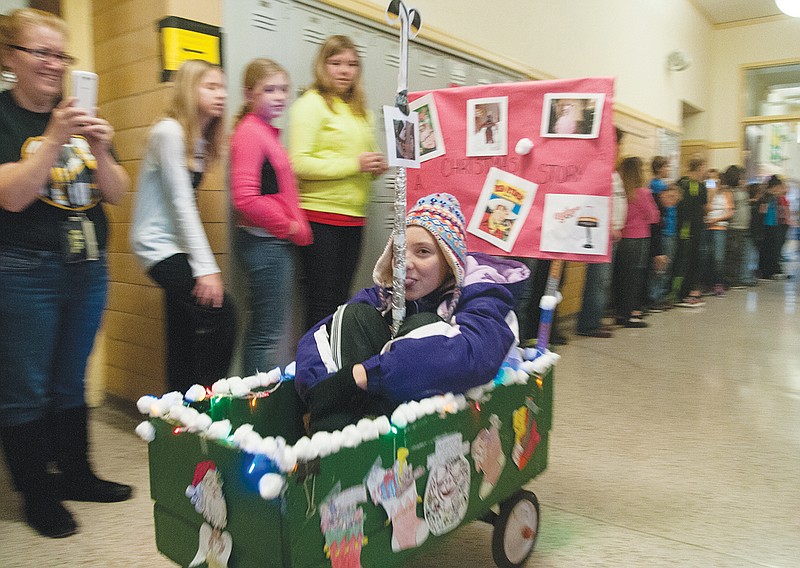 Fulton Middle School student Hailie Acton presses her tongue to a fake pole to imitate the movie, "A Christmas Story." In the movie, the character Flick's tongue is stuck to an icy post after a friend "triple dog dares" him to lick the post. The wagons were judged during the parade. The first place winner was from teacher Kathryn Walker's class. Her students represented the movie, "Polar Express" and will receive a pizza party when they return from the winter break. Second place was a tie between Jan Bailey's class and Barb Barkho's class. Both wagons imitated "A Charlie Brown Christmas." Darren's Masek's class took third place with a wagon that represented "How the Grinch Stole Christmas." The Fulton Middle School Student Council organized the event.