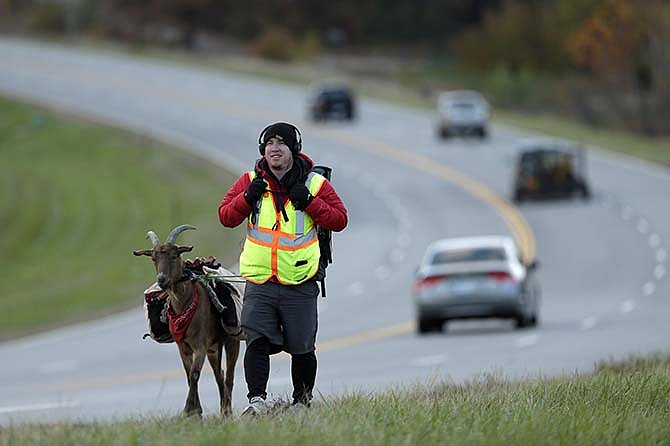 In this Wednesday, Nov. 6, 2013 photo, Steven Wescott walks with his goat, LeeRoy Brown, along a street in Lenexa, Kan. The two have been walking since May 2, 2012 from Seattle, Wash. to New York City to raise money to build an orphanage in Kenya. 
