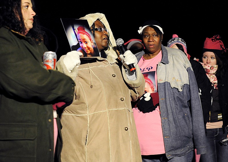 Cynthia White holds up a photo of her great-niece, Eyana White, 12, as she stands Monday during a candlelight vigil surrounded by close friends and family while imploring the gathered crowd to take action and to not let an innocent child die in vain. According to those closest to the seventh grader, relentless bullying at school and online led Eyana to commit suicide by hanging herself in her home Dec. 17.