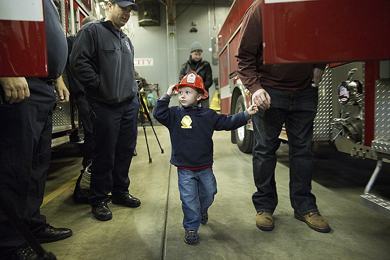 Honorary fireman Kingston McGill holds his father Jesse's hand before boarding a fire engine at Fire Station 1 in Jefferson City.