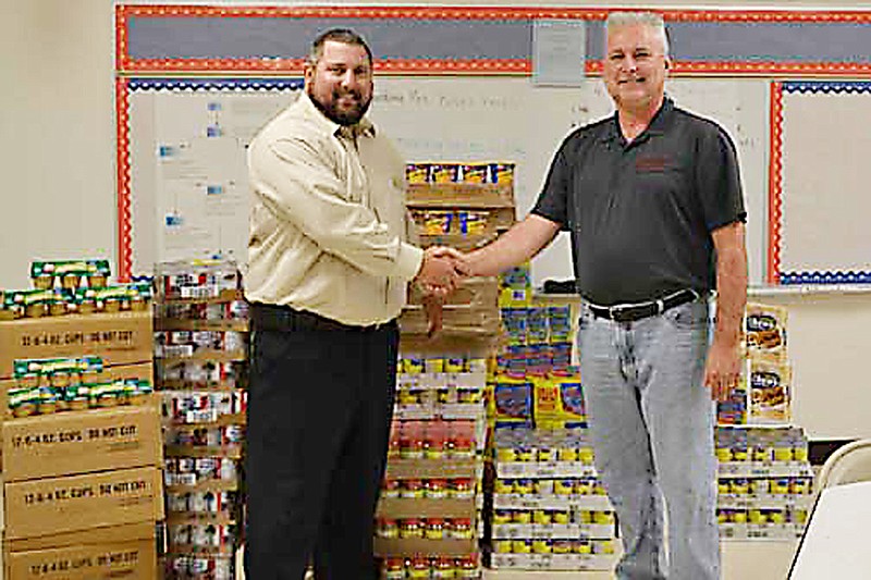 California Elementary Principal Daniel Williams receives Buddy Pack donation from Burgers' Smokehouse representative Randy Less.