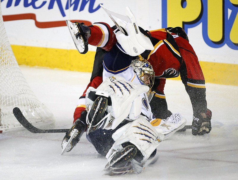 Blues goalie Jaroslav Halak ducks as Lance Bouma of the Flames dives over him during the second period of Tuedsay's game in Calgary, Alberta.
