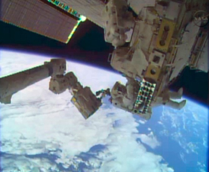 In this image taken from video provided by NASA, astronauts Rick Mastracchio, top, and Michael Hopkins work to repair an external cooling line on the International Space Station on Tuesday, Dec. 24, 2013, 260 miles above Earth. The external cooling line - one of two - shut down Dec. 11. The six-man crew had to turn off all nonessential equipment, including experiments. 