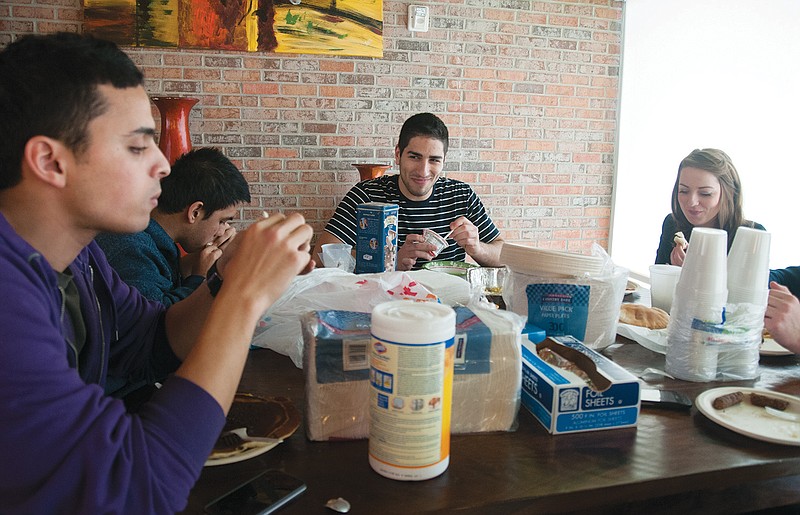 Hussein Attara (center), Westminster College student and president of the International Club, smiles while eating yogurt during a brunch on Dec. 25 at Sloss Hall on the Westminster campus.