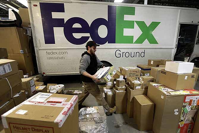 In this Dec. 16, 2013 file photo, package handler Chris Addison arranges packages before loading a delivery truck at a FedEx sorting facility in Kansas City, Mo. 