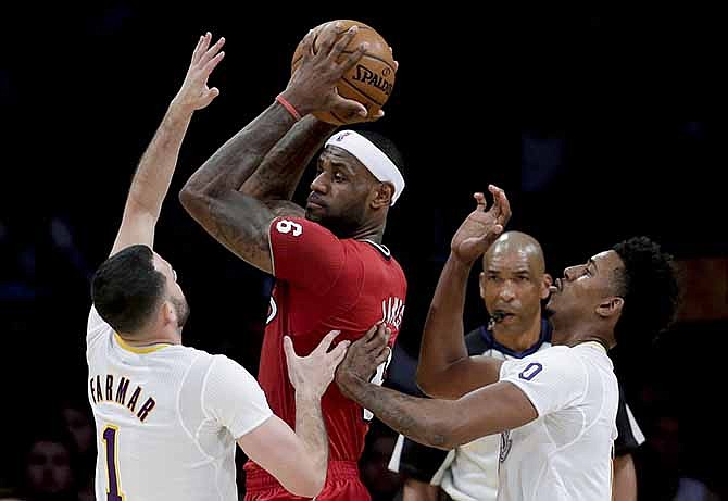 Miami Heat forward LeBron James, middle, is double-teamed by Los Angeles Lakers' Jordan Farmar, left, and Nick Young during the first half of an NBA basketball game in Los Angeles, Wednesday, Dec. 25, 2013.