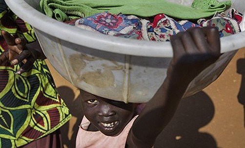 A young displaced girl carries a basket of laundry Friday inside a United Nations compound, which has become home to thousands of people displaced by the recent fighting, in Juba, South Sudan. 