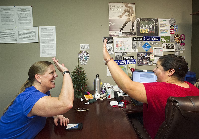 Lisa Donlea, left, and Susan Roberts, a certified enrollment officer, celebrate after working on Donlea's federal health insurance exchange enrollment online for one hour and 47 minutes in Laguna Beach, Calif.