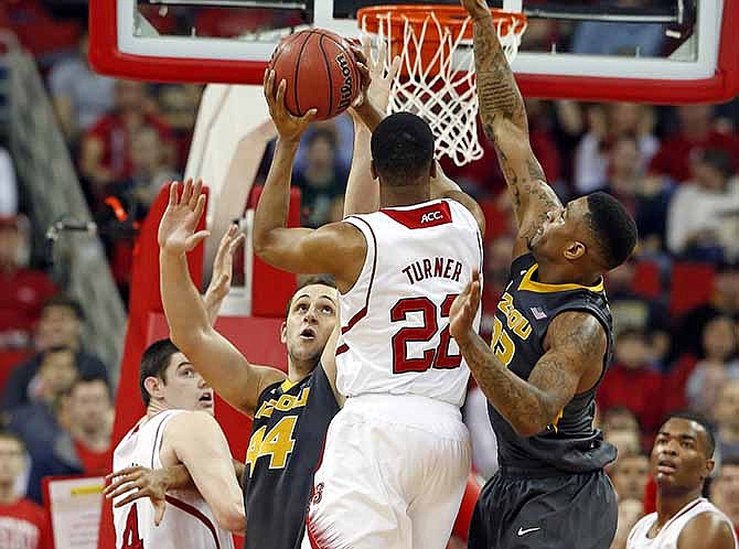 North Carolina State's Ralston Turner (22) drives the ball between Missouri's Earnest Ross, right, and Ryan Rosburg (44) during the first half of an NCAA college basketball game in Raleigh, N.C., Saturday, Dec. 28, 2013.