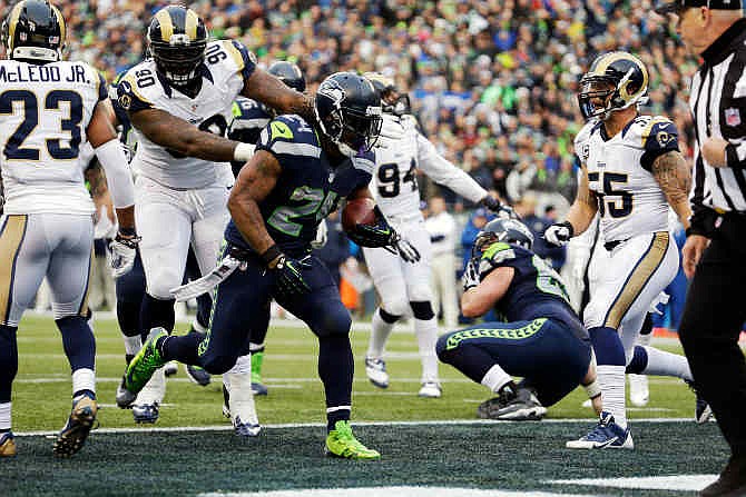 Seattle Seahawks running back Marshawn Lynch runs for a touchdown ahead of St. Louis Rams defensive tackle Michael Brockers (90) in the second half of an NFL football game, Sunday, Dec. 29, 2013, in Seattle. 