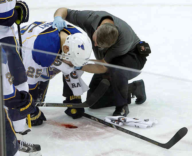 A trainer tends to St. Louis Blues right wing Chris Stewart (25) after Stewart took a puck to the face during the first period of an NHL hockey game against the Minnesota Wild in St. Paul, Minn., Tuesday, Dec. 31, 2013. 