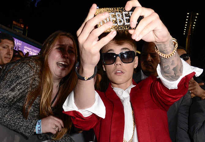 Singer Justin Bieber takes a photo with a fan at the premiere of the feature film "Justin Bieber's Believe" at Regal Cinemas L.A. Live on Wednesday, Dec. 18, 2013, in Los Angeles.