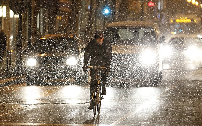 A lone cyclist works his way down Walnut Street in Philadelphia, avoiding traffic but not the falling snow Thursday night,. 
