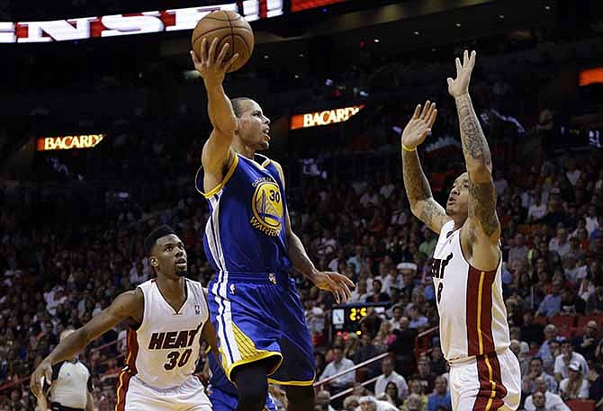 Golden State Warriors' Stephen Curry (30) shoots between Miami Heat's Norris Cole (30) and Michael Beasley (8) during the second half of an NBA basketball game, Thursday, Jan. 2, 2014, in Miami. The Warriors defeated the Heat 123-114.