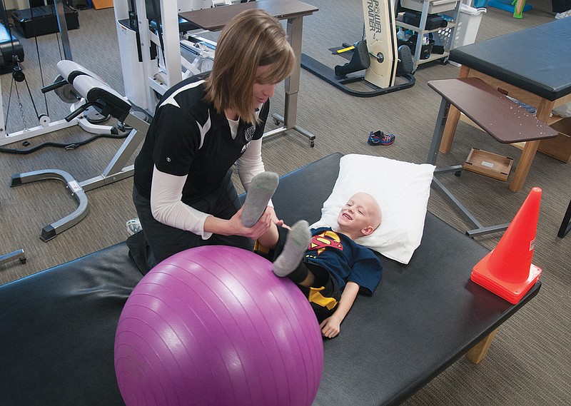 Kelly Nickelson, physical therapist with Atlas Physical Therapy in Fulton, stretches five-year-old Sam Santhuff's legs at the end of a session on Thursday. Santhuff was diagnosed with cancer which has caused neuropathy in his hands and feet. Nickelson works with Santhuff to strengthen those areas. She met and befriended Santhuff's mother, Cassie Santhuff, through a young parents group at First Christian Church in Fulton, and now volunteers her time to give Sam Santhuff physical therapy.