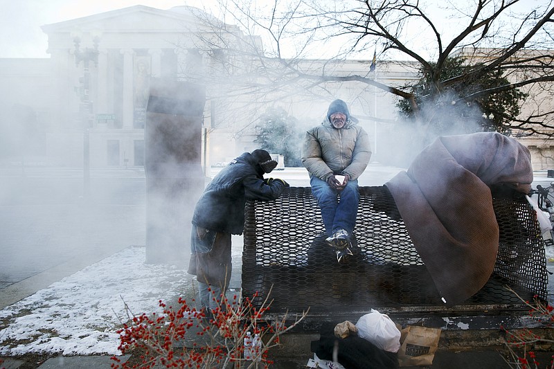 Four homeless men warm themselves on a steam grate by the Federal Trade Commission, blocks from the Capitol, during frigid temperatures in Washington, D.C., on Saturday, January 4, 2014.