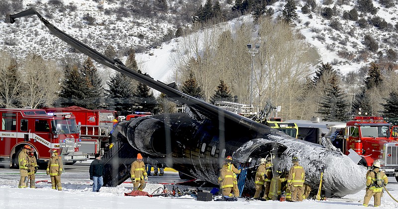 Emergency crews work near a passenger plane that crashed Sunday upon landing at the Aspen-Pitkin County Airport in Aspen, Colo.
