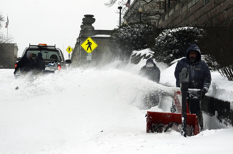 Raleigh Nott with the state Division of Facilities Management removes snow from the sidewalk in front of the Missouri Supreme Court building and the Broadway State Office Building late Sunday afternoon.