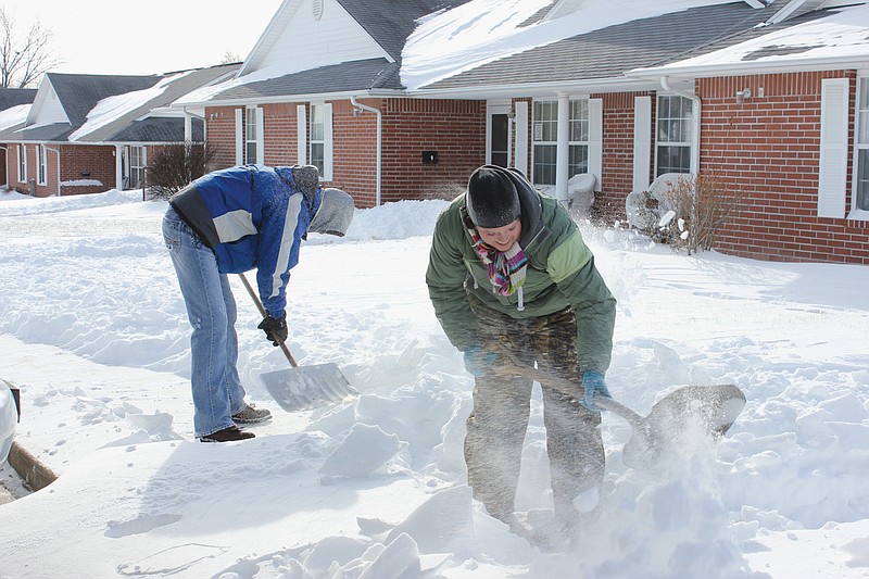 Amanda Atterberry and Brad Luether battle high winds, below-zero temperatures and drifting snow as they shovel out sidewalks at Fulton Senior Apartments off Saint Eunice Road Monday. 