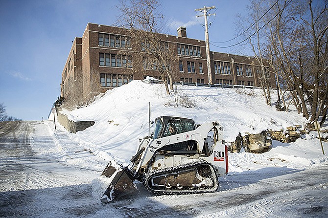 Harvey Kempker, of Kempker Trucking, uses a Bobcat to remove snow from the Simonsen Ninth Grade Center sidewalks Monday afternoon. Many schools were closed Monday and remain closed today as a result of below freezing temperatures. 