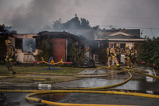 Orange County Fire Authority firefighters survey the damage of a house fire on Wednesday in Santa Ana, Calif. Authorities say two people have been killed and four others injured in the early morning fire at a group home for developmentally disabled adult women. 