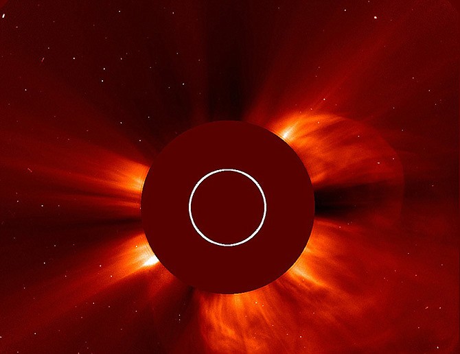 In this Tuesday image made available by NASA, a giant cloud of solar particles, a coronal mass ejection, explodes off the sun, lower right, captured by the European Space Agency and NASA's Solar and Heliospheric Observatory. The sun is obscured to show the atmosphere around it. 