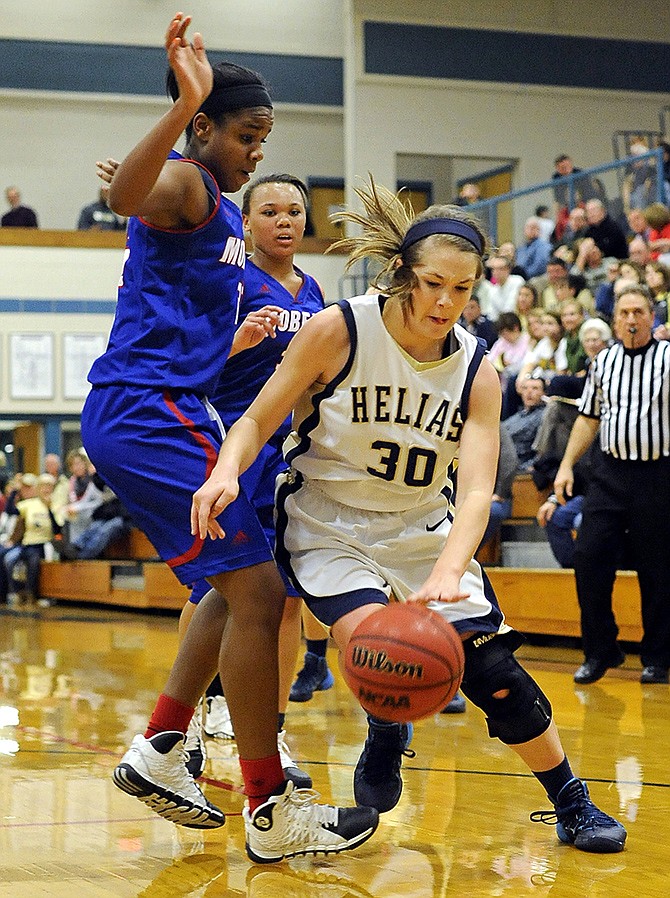 Helias' Emma Wyrick drives past Moberly center Mia Davis (33) on Friday night at Rackers Fieldhouse.