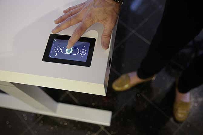 Jennifer McNally, a head of marketing at Stir, demonstrates on the Kinetic Desk at the International Consumer Electronics Show on Wednesday, Jan. 8, 2014, in Las Vegas. With built-in motorized legs, the height of the desk can be adjusted by using a touchscreen controller located in the corner of the desk.