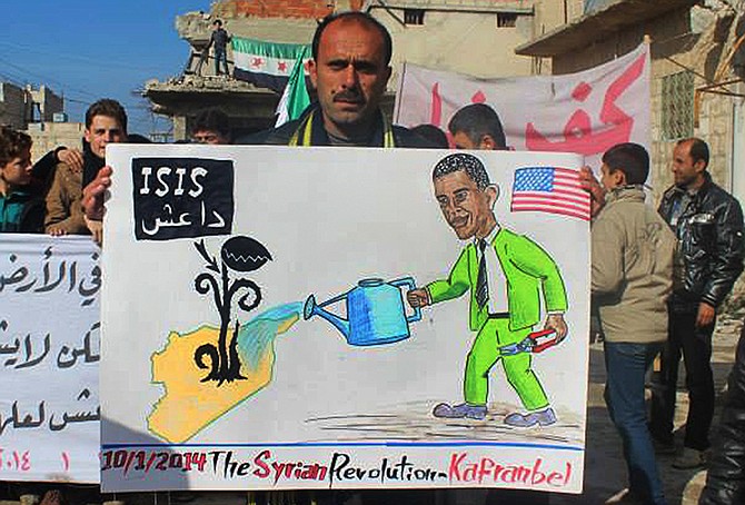 A protester holds a placard depicting U.S. President Barack Obama during a demonstration Friday in Kafr Nabil town, Idlib province, northern Syria. Rebel-on-rebel fighting between an al-Qaida-linked group and an array of more moderate and ultraconservative Islamists has killed nearly 500 people over the past week in northern Syria. 