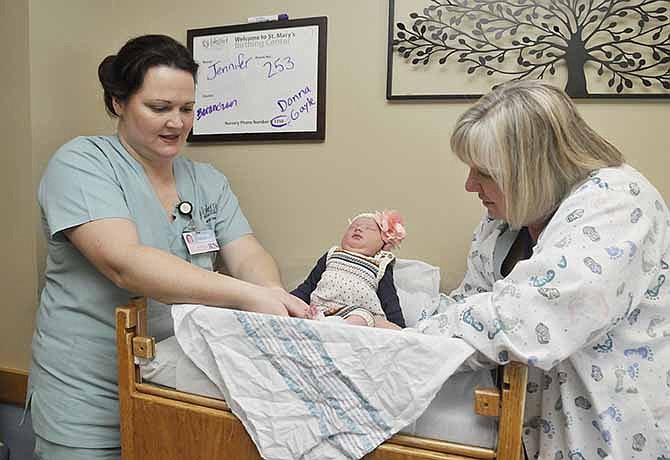 Robyn Lehmen, left, and Gayle Vice prepare an infant for her trip home. Both are registered nurses in St. Mary's Health Center Blessed Beginnings OB ward. The baby's parents took the 3-day-old home to join her older brother.