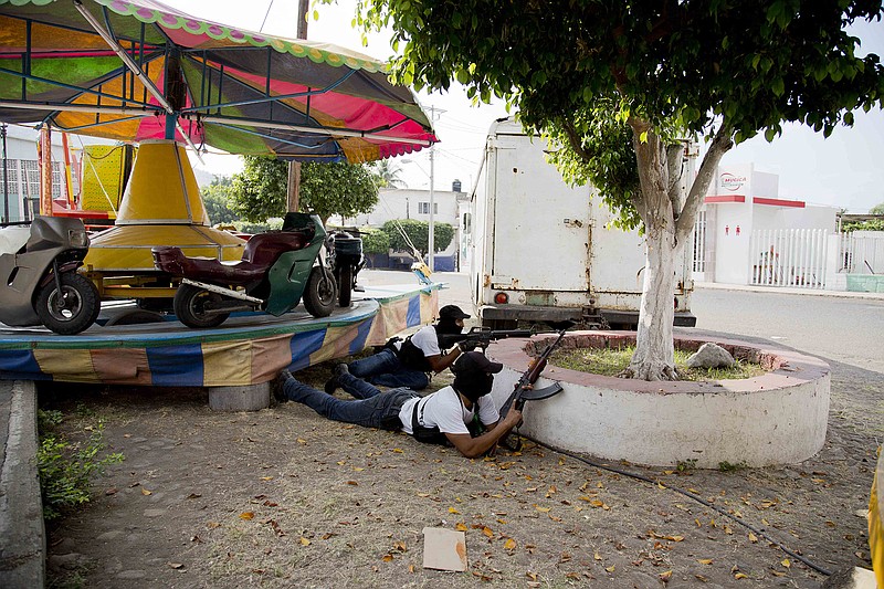 Men belonging to the Self-Defense Council of Michacan, (CAM), take cover Sunday during a firefight while trying to flush out alleged members of the Knights Templar drug cartel from the town of Nueva Italia, Mexico. The vigilantes say they are liberating territory in the so-called Tierra Caliente and are aiming for the farming hub of Apatzingan, said to be the cartel's central command. Mexican military troops are staying outside the town and there are no federal police in sight. 