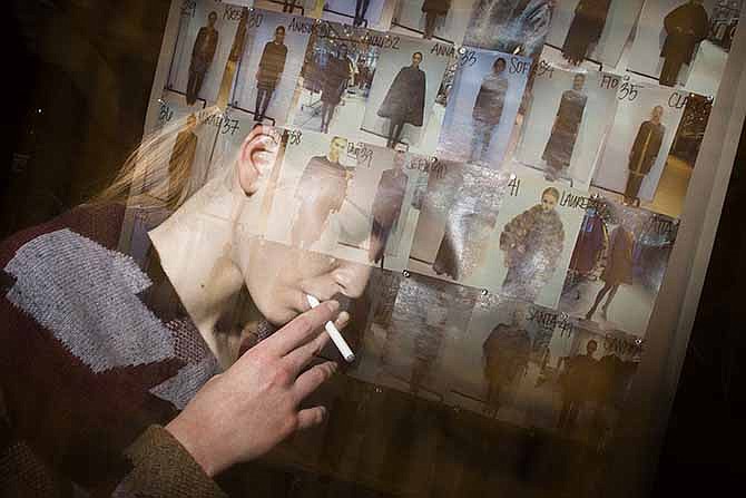  In this Feb. 10, 2013 file photo made with multiple flash exposures, a model pulls on an electronic cigarette backstage before the Chado Ralph Rucci fashion show in New York. 