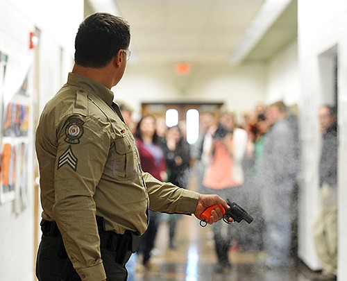 Sgt. Ralph Lemongelli fires a starter pistol Friday in the hallway at Blair Oaks Middle School as teachers and staff from all three Blair Oaks schools attend intruder training held in the middle school. They learned tactics to keep students and themselves safe in the case of a gun-wielding intruder in the school building.